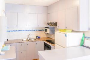 La cuisine est équipée de placards blancs et d'un réfrigérateur blanc. dans l'établissement SOL NAIXENT, à Fornells