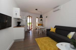 a living room with a black couch and a kitchen at Vila Nainer in Pag