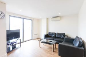 a living room with a black couch and a tv at Modern 2 Bed 2 Bath Apartment Hyde Park in London
