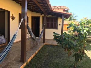 a porch with a hammock outside of a house at Casa de Praia 4qtos em Saquarema! in Saquarema