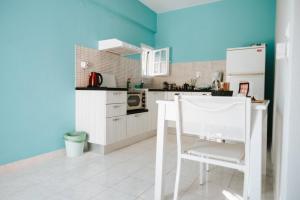 a kitchen with a white chair and a blue wall at Jerry Apartments in Svoronata