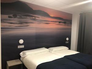 a bedroom with a bed with a painting on the wall at Hostel El Paloma in Santoña