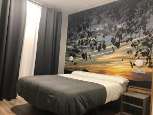 a bedroom with a bed with a painting on the wall at Hostel El Paloma in Santoña