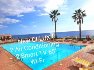 a swimming pool with a view of the ocean at DELUXE SeaView-SUNSETS !TRANSFE-R inc! POOL,2AirCond,2TV65",600Mb Dishwasher,,2 BEACHes,ANFI-view in Patalavaca
