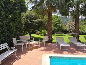 een groep stoelen en tafels naast een zwembad bij Villa dei leoni in Santa Tecla