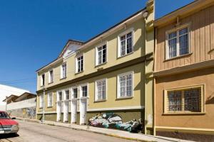 a yellow building with white windows on a street at Casa Capilla in Valparaíso