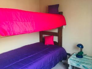 Dormitorio con litera con sábanas rosas y moradas en Casa el Tihue Puerto Varas en Puerto Varas