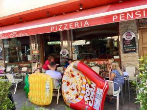 un grupo de personas sentadas fuera de una pizzería en Pension Casa Austria, en Calella