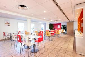 une salle à manger avec des tables et des chaises dans une cafétéria dans l'établissement Premiere Classe Paris Ouest Pont De Suresnes, à Suresnes