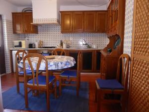 a kitchen with a table and chairs and a kitchen with wooden cabinets at CASA BERIMBAU in Vila Nova de Milfontes