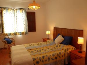 a bedroom with a bed and two lamps and a window at CASA BERIMBAU in Vila Nova de Milfontes