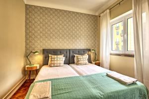 リスボンにあるAlmirante 3-Four Bedroomsのベッドルーム1室(緑の毛布、窓付)