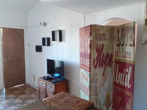 ein Wohnzimmer mit einem TV, einem Sofa und einer Tür in der Unterkunft Precioso apartamento en el centro de La Paloma a menos de dos cuadras de la playa in La Paloma