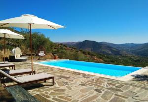 a swimming pool with two chairs and an umbrella at Quinta Vale de Carvalho in Pinhal do Douro