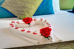 a cake with three roses on a bed at VR Auckland City in Auckland