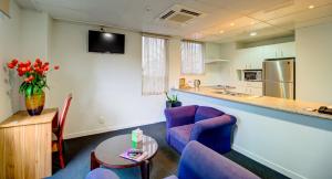 a living room with blue chairs and a kitchen at Ascotia Off Queen in Auckland