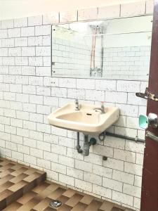 Baño blanco con lavabo y espejo en Lestari Guesthouse en Padang