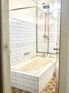 a bath tub in a white tiled bathroom at Lestari Guesthouse in Padang