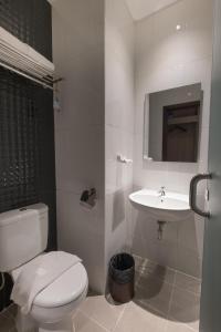 a white bathroom with a toilet and a sink at Hotel 88 ITC Fatmawati Jakarta By WH in Jakarta