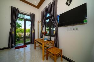 a living room with a wooden table and a television at Hoi An Garden Sea Homestay in Hoi An