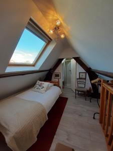 1 dormitorio en el ático con cama y ventana en Les Alouettes B&B, en Hardecourt-aux-Bois