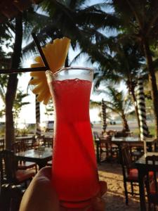 a person holding a red drink with a yellow flower in it at Tony Home and Restaurant in Karon Beach