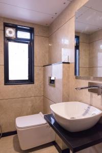 ein Bad mit einem Waschbecken, einem WC und einem Fenster in der Unterkunft Hotel Sangat Regency in Bhopal
