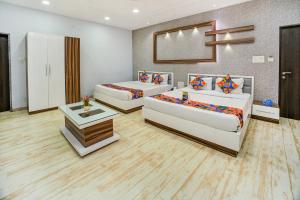 Habitación con 3 camas, mesa y espejo. en FabHotel Bee Town, en Indore