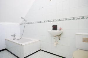 ein weißes Bad mit einem Waschbecken und einem WC in der Unterkunft RedDoorz Plus near Stadion Wijaya Kusuma in Cilacap