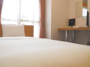 1 dormitorio con cama blanca y ventana en Hotel Tetora Ikebukuro, en Tokio
