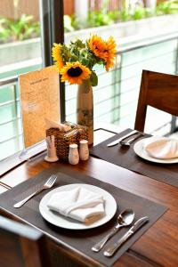 a table with plates and a vase with sunflowers on it at Entire 5 bedrooms - Pool Sun Paradise Villa in Hiếu Nhơn