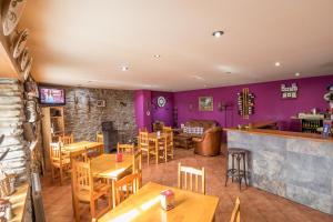 um restaurante com paredes roxas e mesas e cadeiras de madeira em Casa Rural La Fuente em Tejedo del Sil