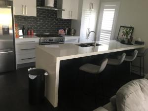 a kitchen with a sink and a counter with stools at Executive Villa, private 2 bedroom in ideal location in Bathurst