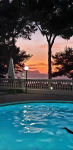 uma piscina com uma árvore e um pôr-do-sol ao fundo em Villa Nunziatella Badia em Trappeto