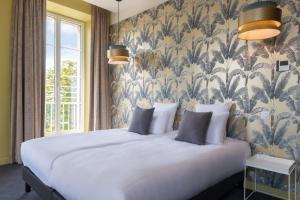 1 dormitorio con 1 cama blanca grande y papel pintado con motivos florales en Château de Tauzies, The Originals Relais en Gaillac