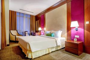 a bedroom with a large bed and a purple wall at Becamex Hotel New City in Thu Dau Mot