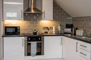a kitchen with white cabinets and a stove top oven at Mc Callstown House Apartment in Ballyclare