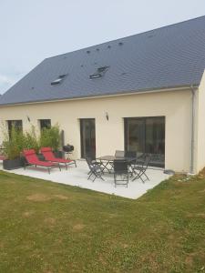 un bâtiment avec une terrasse dotée de chaises rouges et d'une table. dans l'établissement Maison Scherman Bord de Mer, à Saint-Côme-de-Fresné