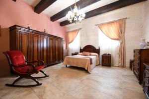 una camera da letto con un letto, una sedia e un lampadario di Ir- Razzett t'Indri a Qala