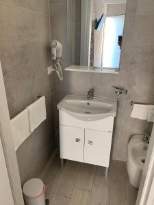 une salle de bain avec un lavabo, des toilettes et un miroir dans l'établissement Residenze La Villa, à Foggia