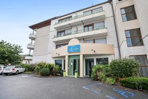 un bâtiment avec une voiture garée sur un parking dans l'établissement Zenitude Hôtel-Résidences Divonne Confort, à Divonne-les-Bains