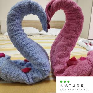 dos toallas con forma de cisnes sentados en una cama en Just nature en Novi Sad