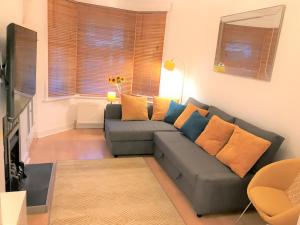 salon z szarą kanapą z pomarańczowymi i niebieskimi poduszkami w obiekcie Seaside House with Parking w mieście Worthing