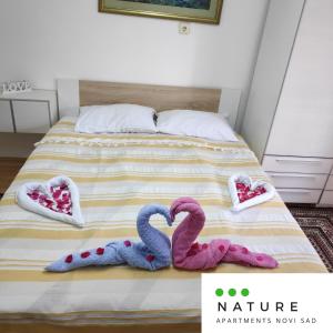 two knitted swans on a bed in a bedroom at Just nature in Novi Sad