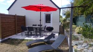 um pátio com uma mesa e cadeiras e um guarda-sol vermelho em Chalet Les dauphins em Saint-Georges-de-la-Rivière