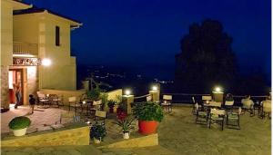 eine Terrasse mit Tischen und Stühlen in der Nacht in der Unterkunft ΡΑΣΤΩΝΗ Πήλιο in Vyzítsa