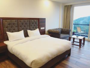 a hotel room with a large bed and a chair at Hotel Chail Residency in Chail
