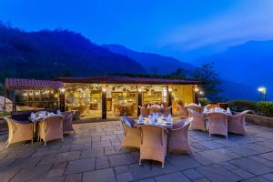 a restaurant with tables and chairs in front of a building at Aloha On The Ganges by Leisure Hotels in Rishīkesh