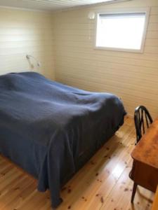 a bedroom with a bed and a table and a window at Hamningberghuset in Havningberg