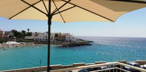 - une plage avec des personnes dans l'eau et un parasol dans l'établissement Residence Lucrezia, à Nardò